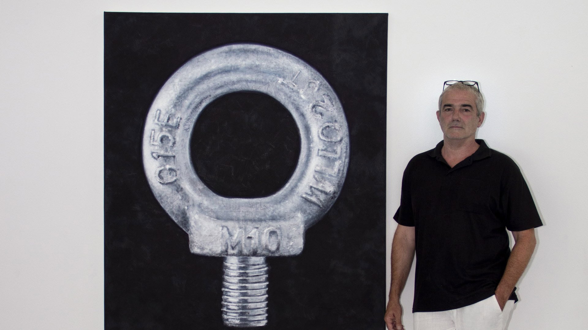 Schlüsselanhänger mit Aufdruck "GIFE" vor schwarzem Hintergrund, Person steht rechts neben dem Objek.