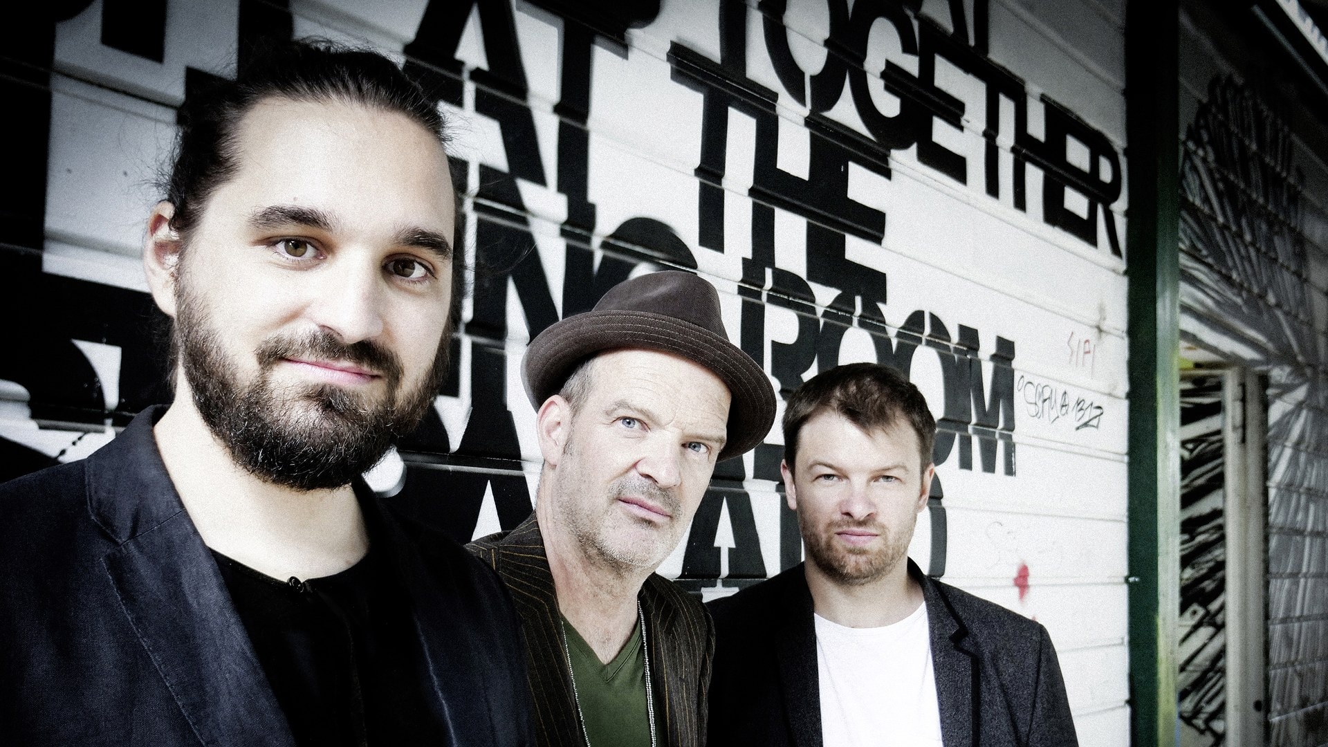 Künstlergruppe vor Wand mit Graffiti-Kunst, kreative Atmosphäre, Fokus auf lokale Kulturveranstaltun.