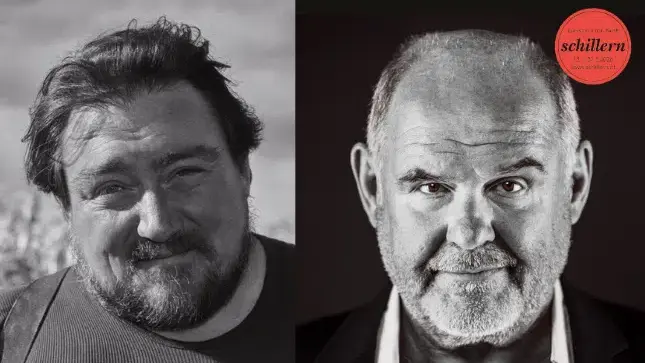 Der Mann mit dunklem Hemd und Bart, lächelnd, in Schwarz-Weiß.